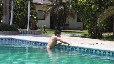 A white man suffering from entering a pool due to the cold water and finally Stock Footage 161965604