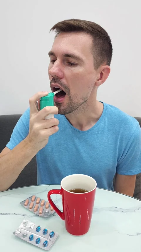 White man using inhaler and red mug and blister packs of pills Stock Footage 282610820