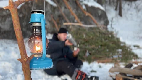 White man warming himself near a hut in the wilderness in winter and a kerosene  Stockbeeldmateriaal 312879150