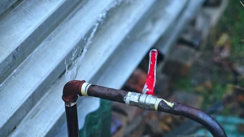 A white man's hand closes a red-handled ball valve and a stream of water st.. Stock Footage 311164521