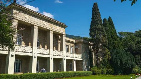 A white mansion with columns surrounded by trees and plants near the coast. Foto stock
