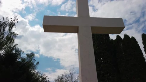 White marble cross front of tall trees. Symbol of crucified Jesus Christ. 4k Video stock 134601680
