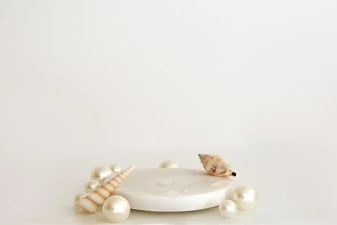 White marble podium with pearls, shells and water drops on the white backgrou Stock Photos