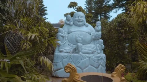 A white marble statue of Budai or the Laughing Buddha, surrounded by children Stock Footage 333372165