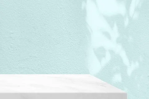 A white marble table corner with on a pale aqua concrete wall. Stock Photos