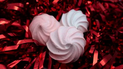White marshmallow on the background of shiny red decorations. Zefir dessert. Stock Photos