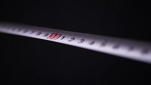 White Measuring Tape Extending Slowly Against Solid Black Background Stock Footage 332663854