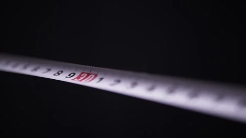 White Measuring Tape Stretching Across a Pitch Black Studio Background Stock Footage 338998347