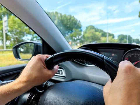 White men hands control a car steering wheel while driving on the road Stock Photos