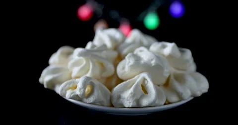 White meringue close-up on a black background and a multicolored garland Stock Footage 164599252