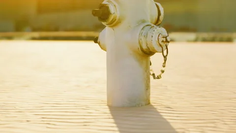 White Metal Fire Hydrant Standing in the Middle of a Vast Desert at Sunrise Stock Footage 348401205