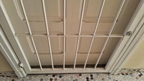 White metal security bars installed over a beige wooden door Stock Photos