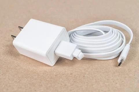 White micro USB cable and a wall charger on a brown background Stock Photos