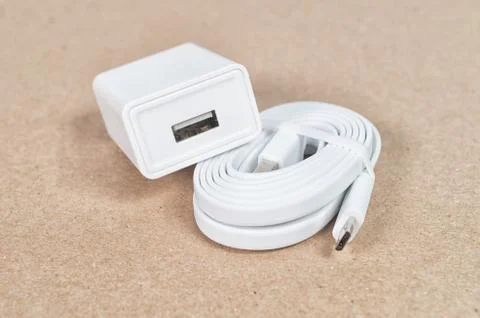 White micro USB cable and a wall charger on a brown background Stock Photos