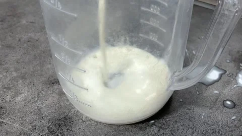 White milk is poured into clear plastic measuring cup Video stock 332574053