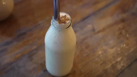 White milkshake from a full bottle on the table. A bottle of milk with straw 库存影片 252305521