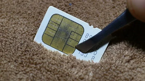 A white mini-SIM card with a golden chip is held with tweezers, extremely close- Stock Footage 149221085