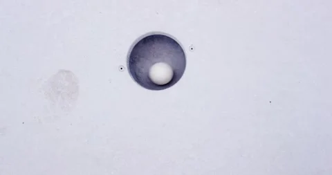 White miniature golf ball rolling across a light lane and dropping into the Vídeo Stock 339898711
