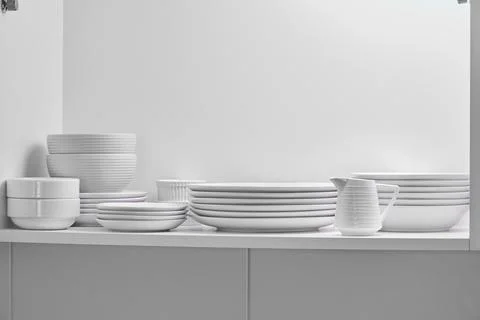White minimalist dishware stacking inside kitchen cabinet Stock Photos