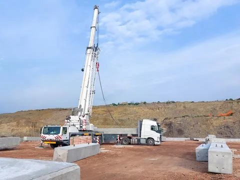 White mobile crane and flatbed semi-truck on a construction site Stock Photos