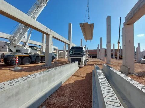 White mobile crane lifting a large precast concrete slab above a semi-truck Stock Photos