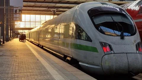 White modern high speed train on railway station at sunset. Stock Photos