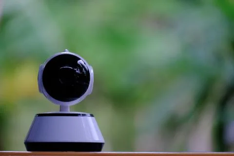 A white modern indoor CCTV camera with internal infrared is rotating to check Stock Photos