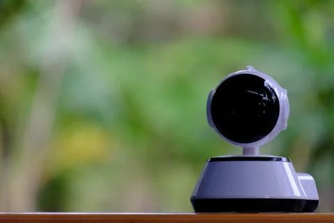 A white modern indoor CCTV camera with internal infrared is rotating to check Stock Photos