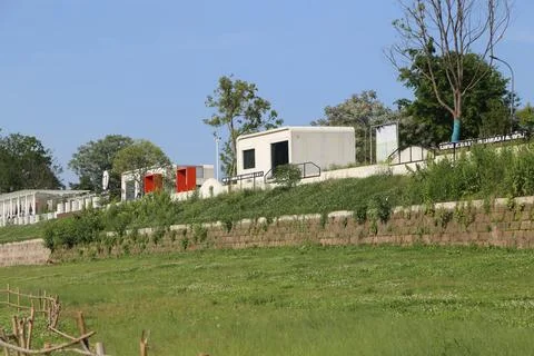 White modular cabins and orange frames on a green hillside with trees and b.. Stock Photos