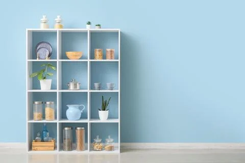 White modular shelving unit with kitchenware and food storage containers agai Stock Photos