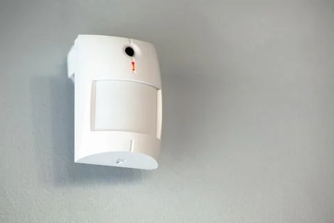 A white motion sensor camera on a gray wall, providing security and surveilla Stock Photos