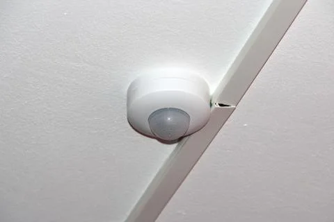 White motion sensor on the ceiling. Security, Automation and Alarm Concept Stock Photos