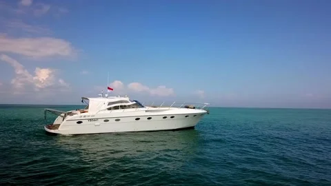 White motor Yacht anchored near the island coastline with Indonesian flag, Stock Footage 131021579