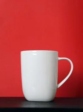 White mug on a black table on a red background for mockup, copy space Foto stock