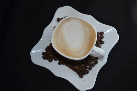 A white mug with cappuccino on a plate covered with grain Stock Photos