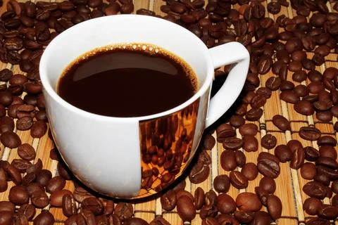 White mug with coffee on the background of beans and mats Stock Photos