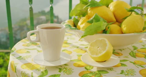 White mug filled with tea on a table adorned with lemons. Sun-kissed scenery Stock Footage 273411419