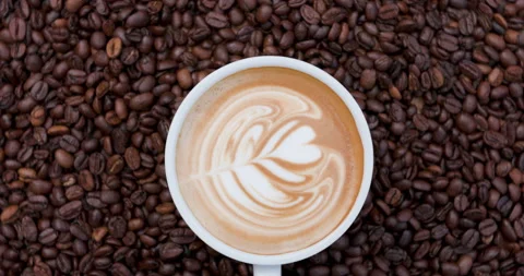 White Mug With Latte Art Rotating On Dark Roasted Coffee Beans Background T.. Stock Footage 340327261