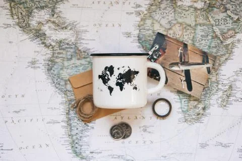 White mug with a map of the world on the background of the world map. Top vie Stock Photos
