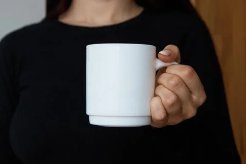 White mug for tea and coffee in the hands of a girl, close-up Stock Photos