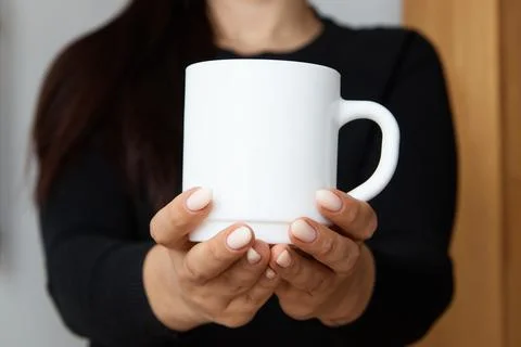 White mug for tea and coffee in the hands of a girl, close-up Stock Photos
