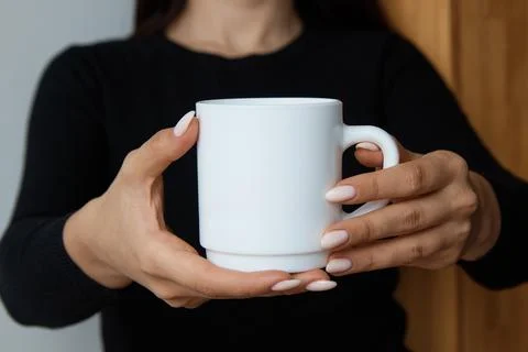 White mug for tea and coffee in the hands of a girl, close-up Stock Photos
