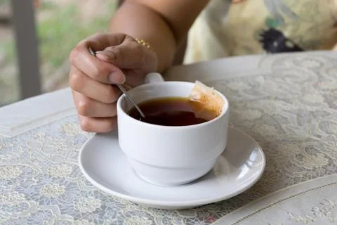 White mug of tea in hand on background of table Stock Photos