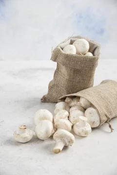 White mushrooms inside rustic baskets on marble background Stock Photos