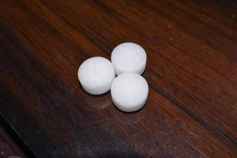 White naphthalene balls on wooden background Stock Photos