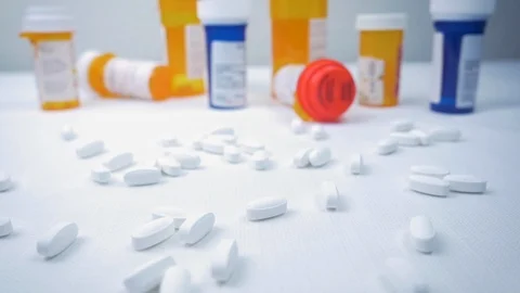 White Narcotic Pills Fall in Slow Motion in front of Prescription Pill Bottles Stock Footage 96526046