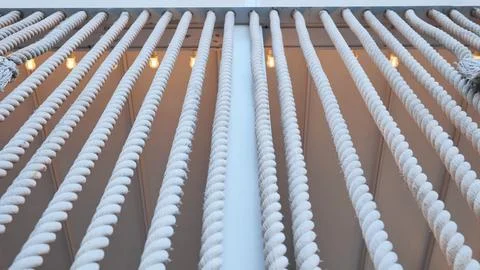 White nautical ropes hanging creating a repeating pattern with warm lights Stock Photos