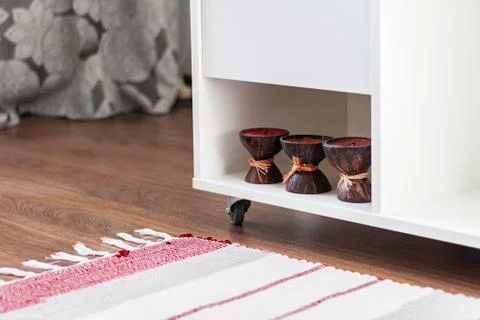 White nightstand with candles, next to a multi-colored rug Stock Photos