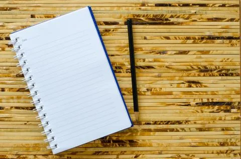 White note book and black pencil on bamboo color background with copy space. Stock Photos