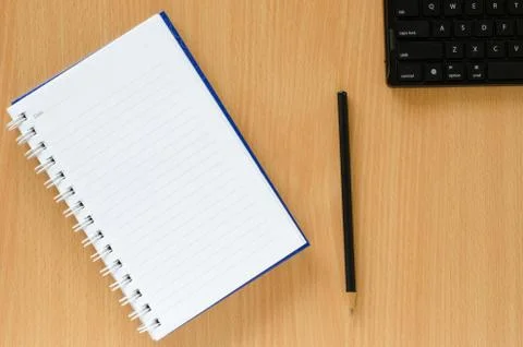 White note book and black pencil and black keyboard  on beech color backgroun Stock Photos
